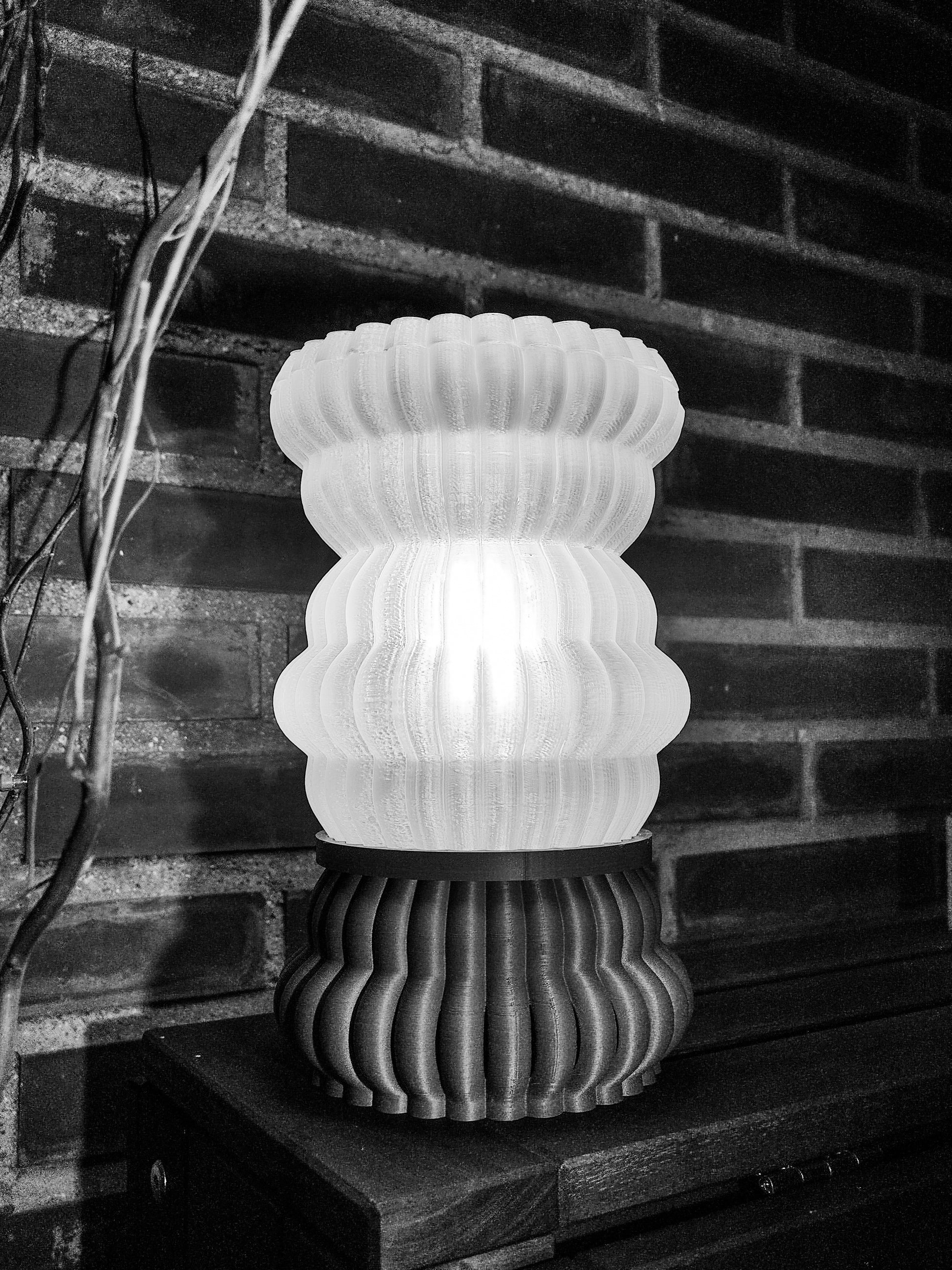 a lamp sitting on top of a table next to a brick wall