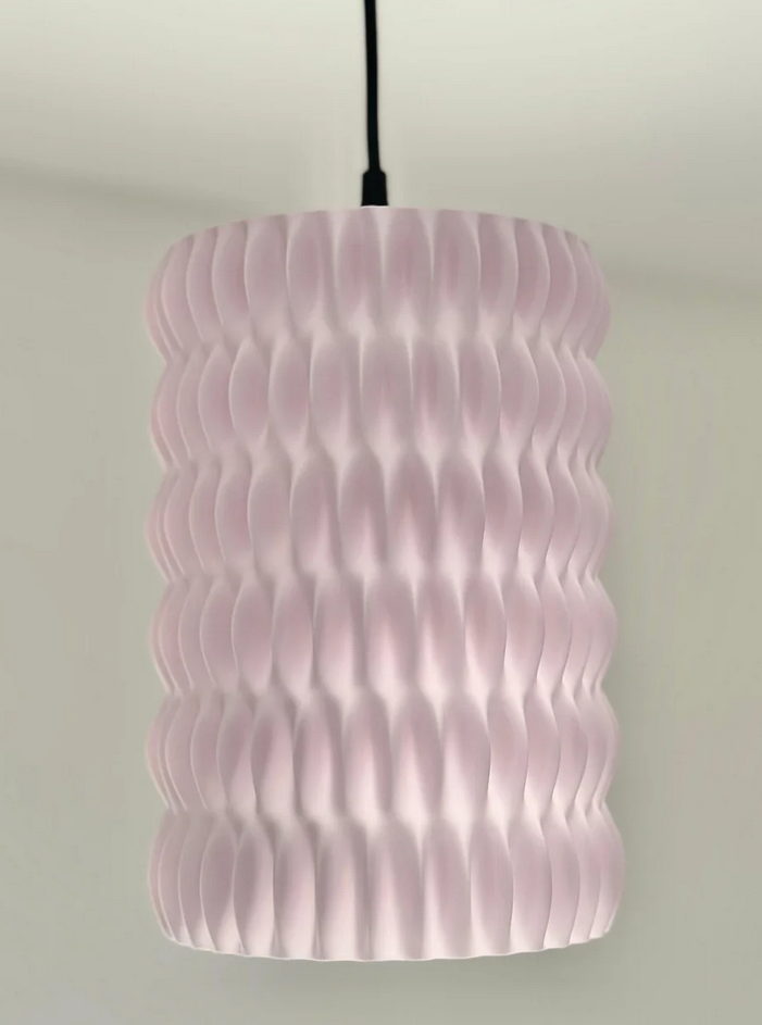 A modern, cylindrical light fixture with a textured, wavy design in a soft pink color.