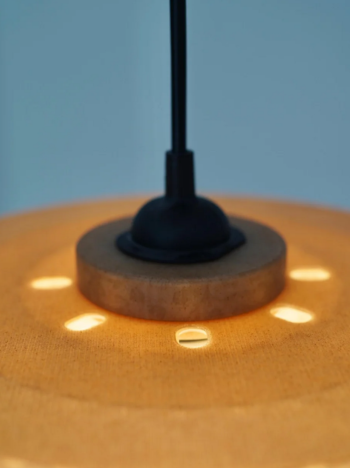 A close-up view of a lampshade with a black base and a circular pattern of light spots on the surface.