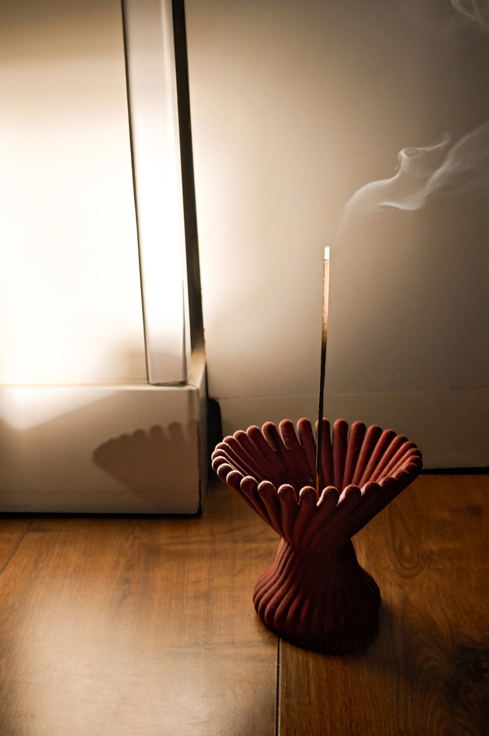 a red vase sitting on top of a wooden floor