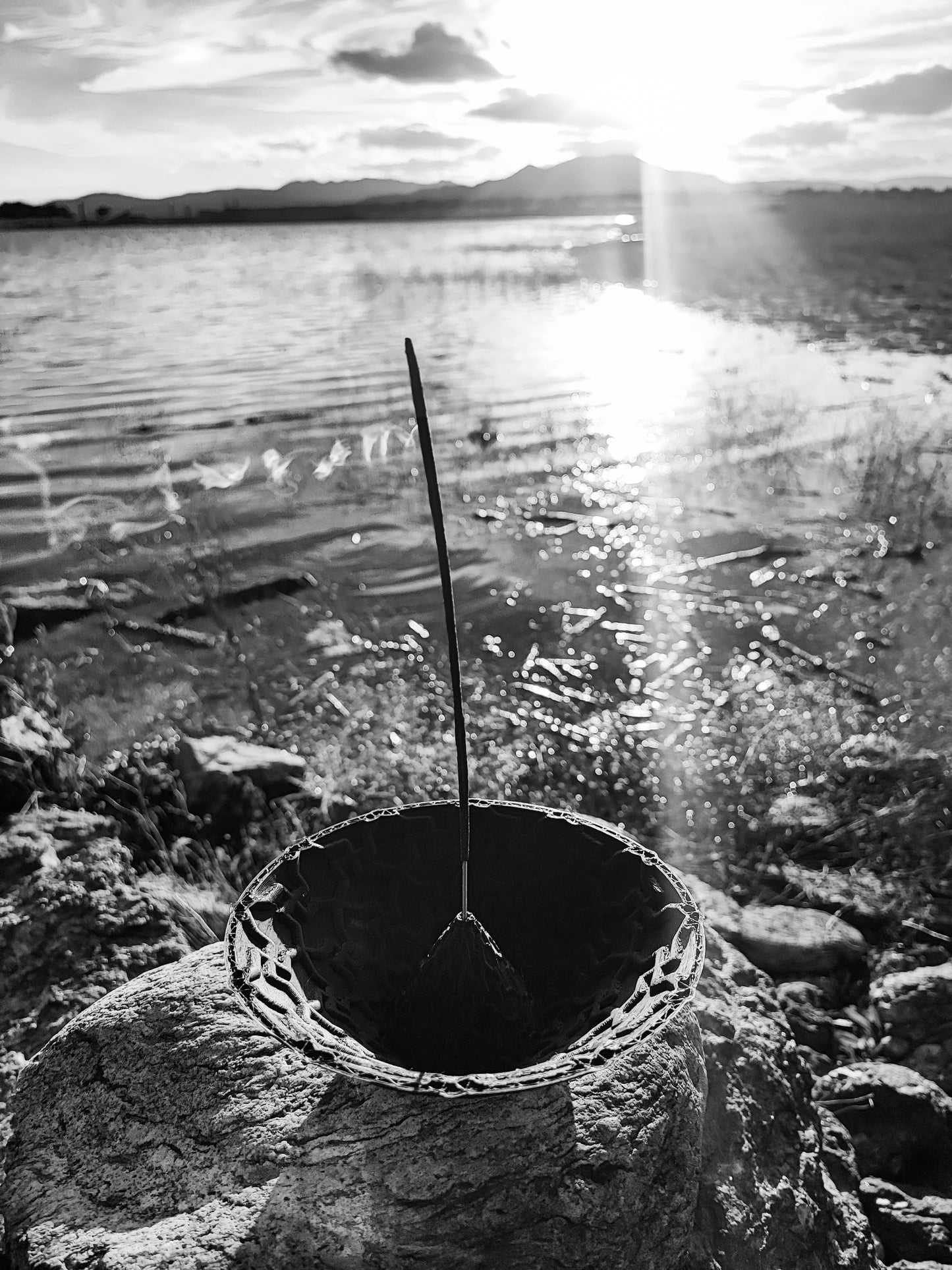a bucket sitting on top of a rock next to a body of water