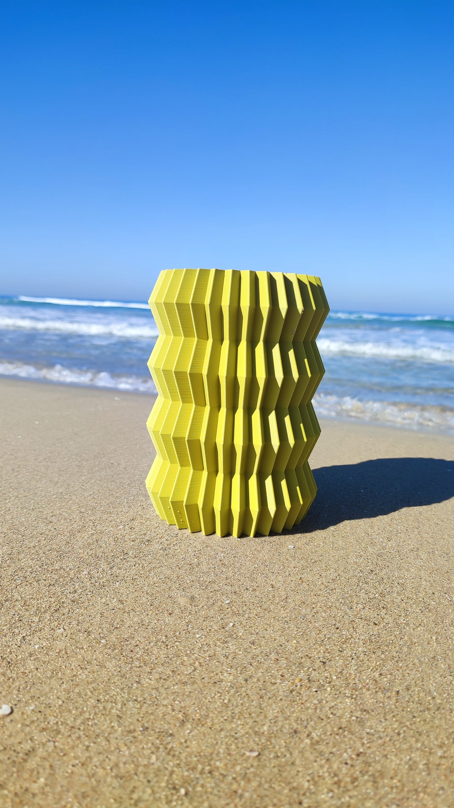 a yellow object sitting on top of a sandy beach