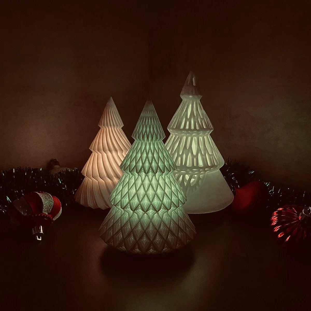 a group of three lighted christmas trees sitting on top of a table