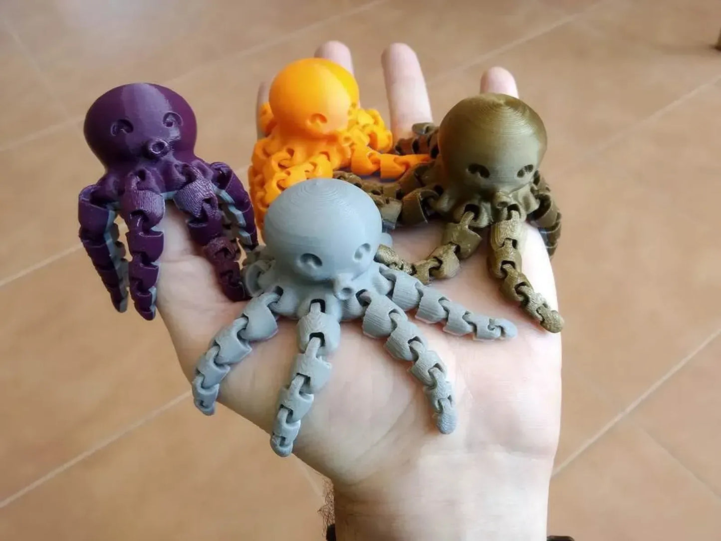a person's hand holding five different colored octopus toys