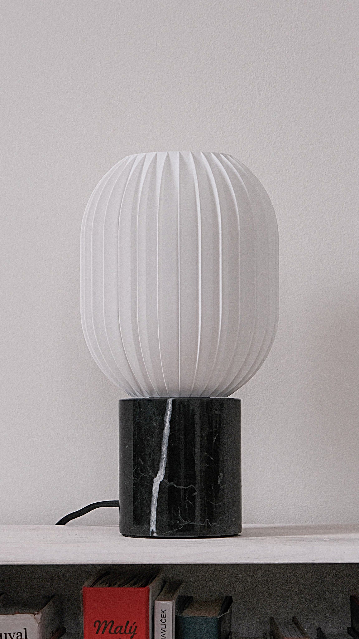 a white lamp sitting on top of a book shelf