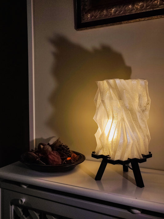 a table lamp sitting on top of a table next to a plate of food