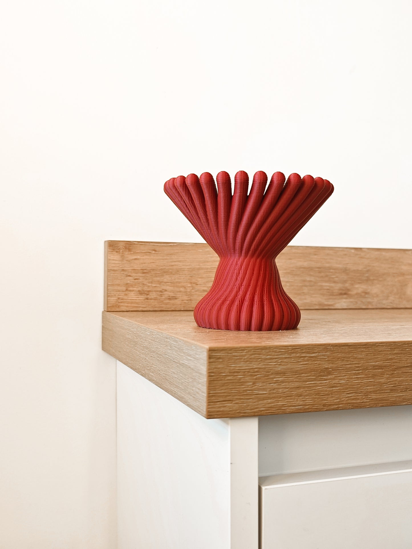 a red vase sitting on top of a wooden table