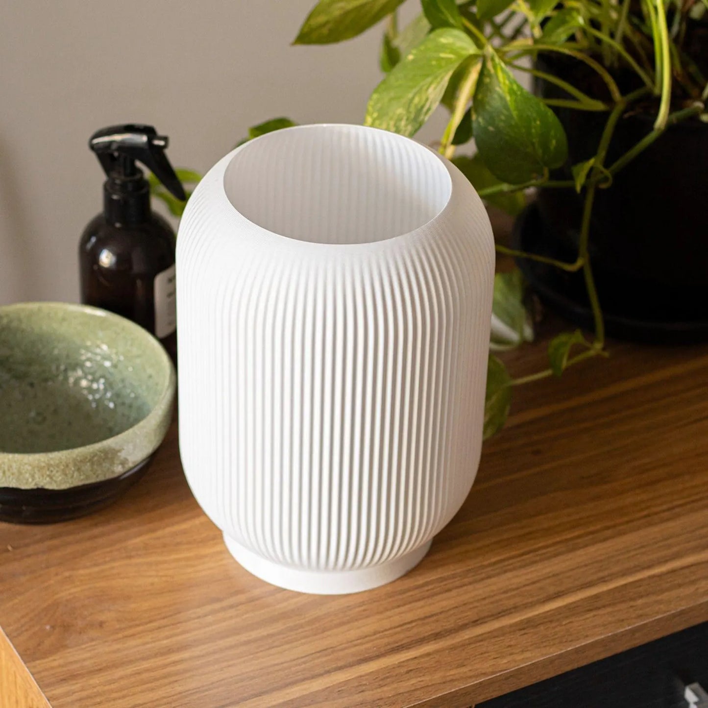 a white vase sitting on top of a wooden table