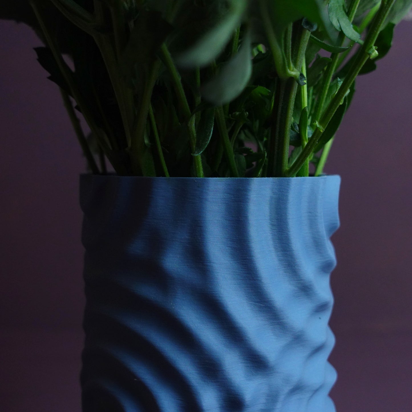 a blue vase filled with lots of green plants