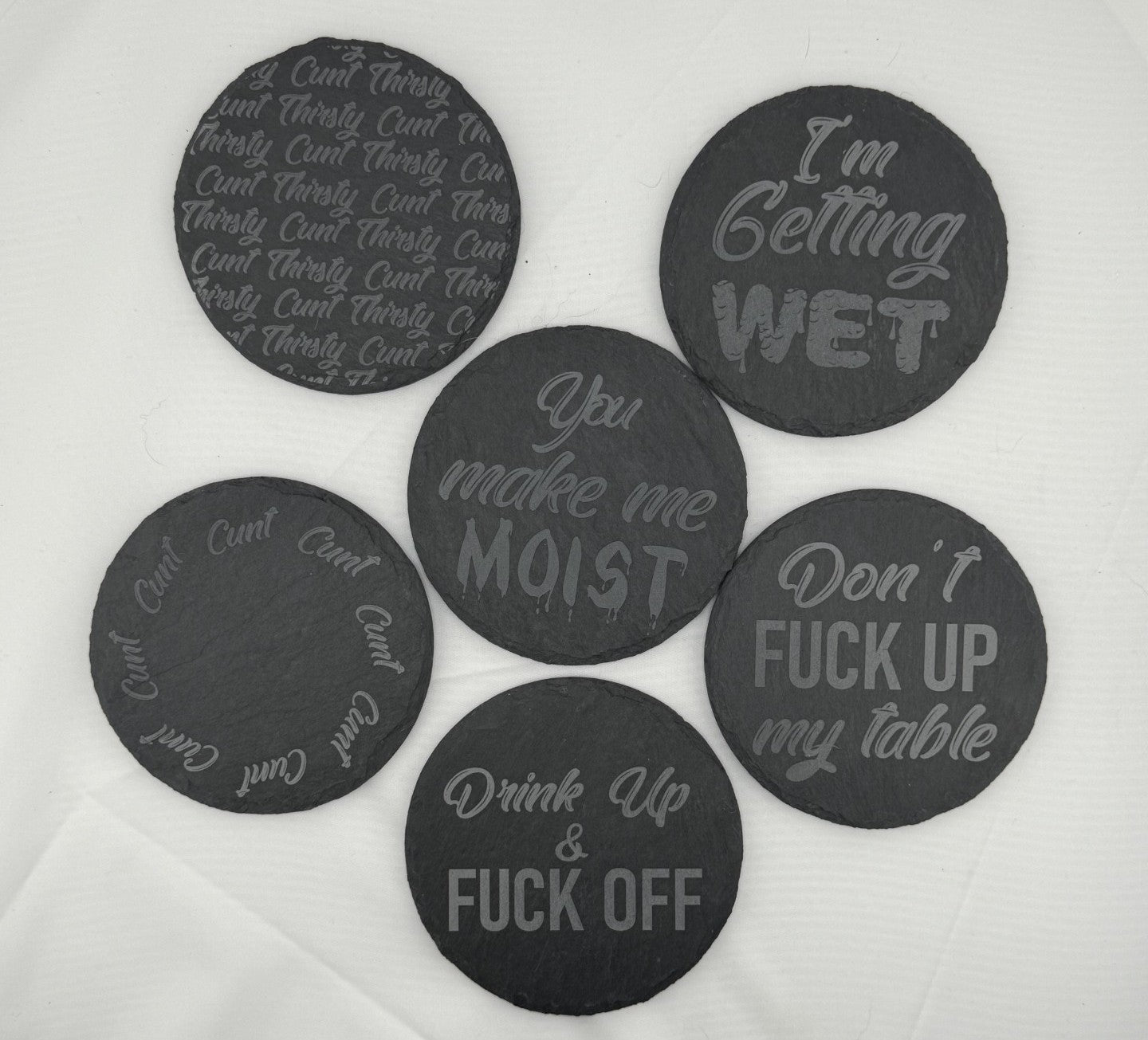 four black slate coasters with writing on them