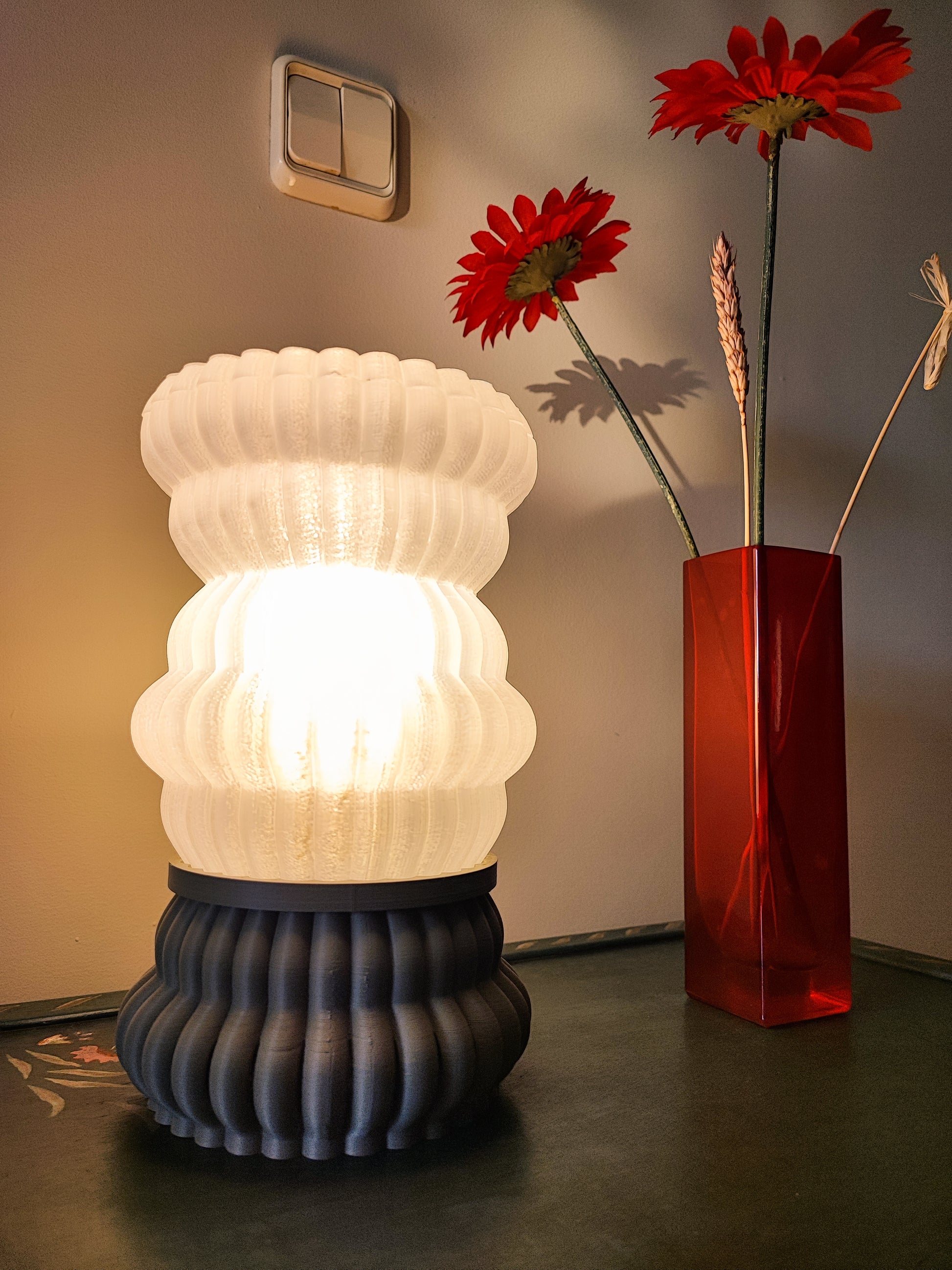 a vase with flowers and a lamp on a table