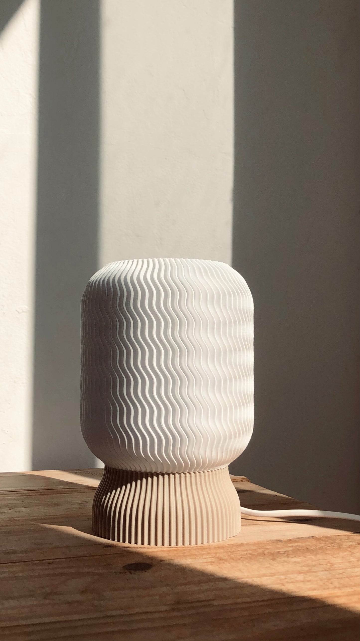 a white vase sitting on top of a wooden table