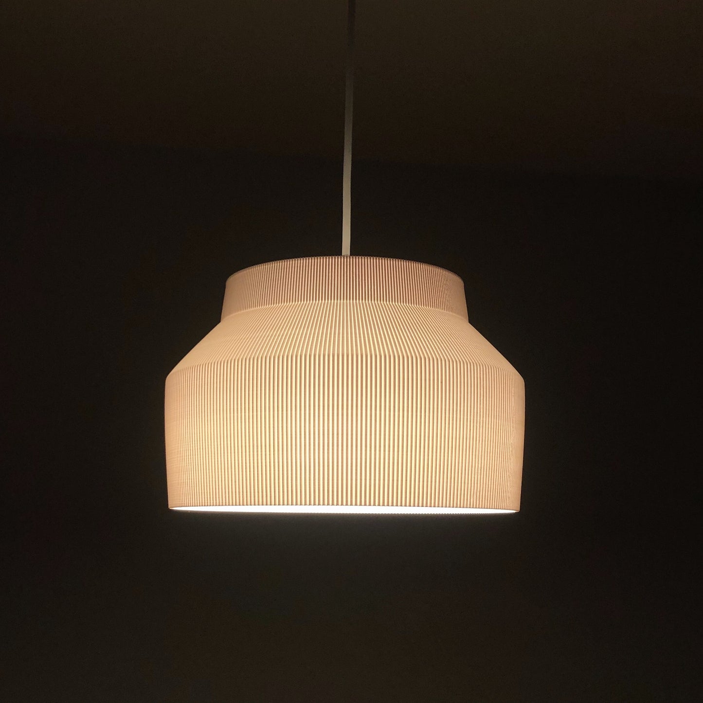 a white light hanging from a ceiling in a dark room