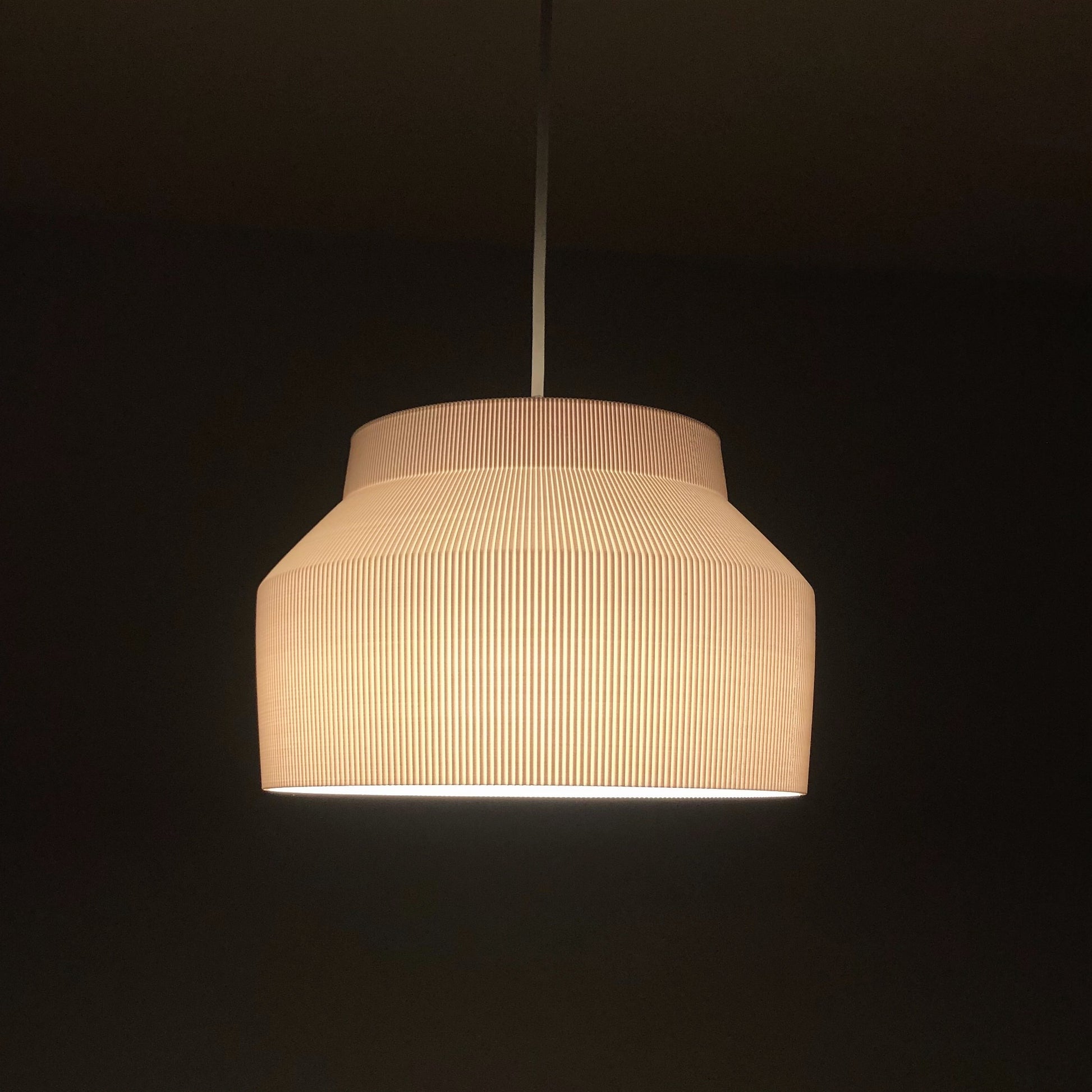 a white light hanging from a ceiling in a dark room