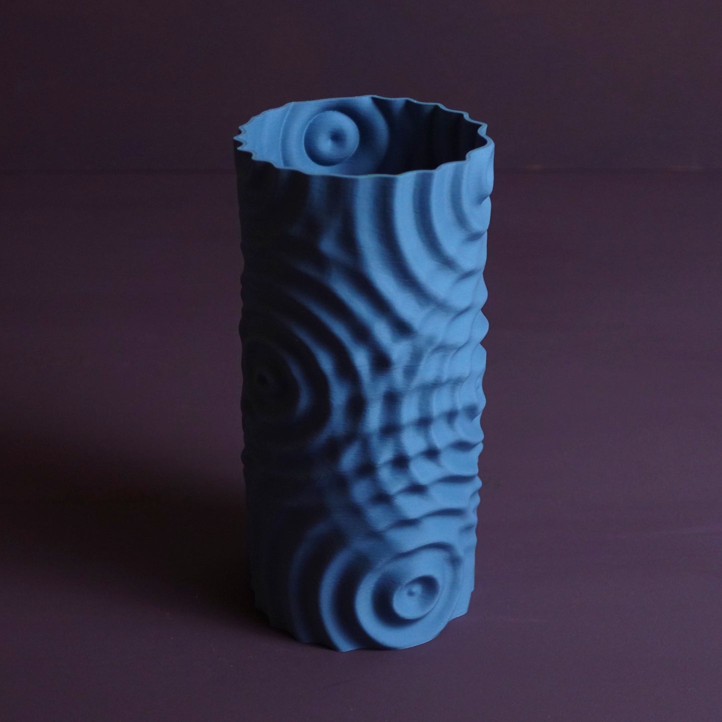 a blue vase sitting on top of a purple table
