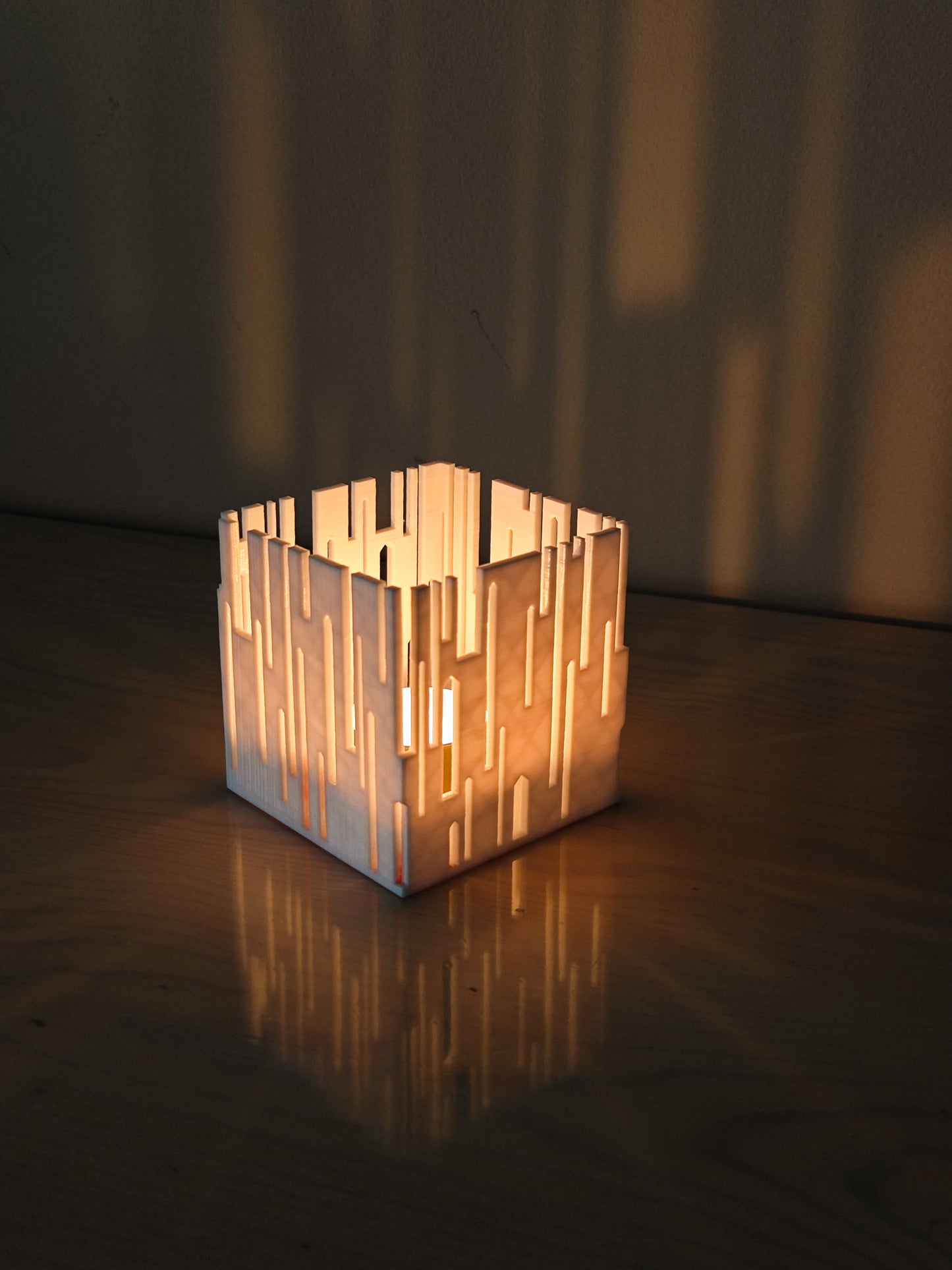 a lit candle holder sitting on top of a wooden table