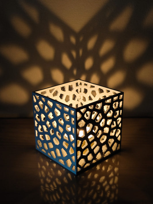 a lit candle sits on a table next to a shadow