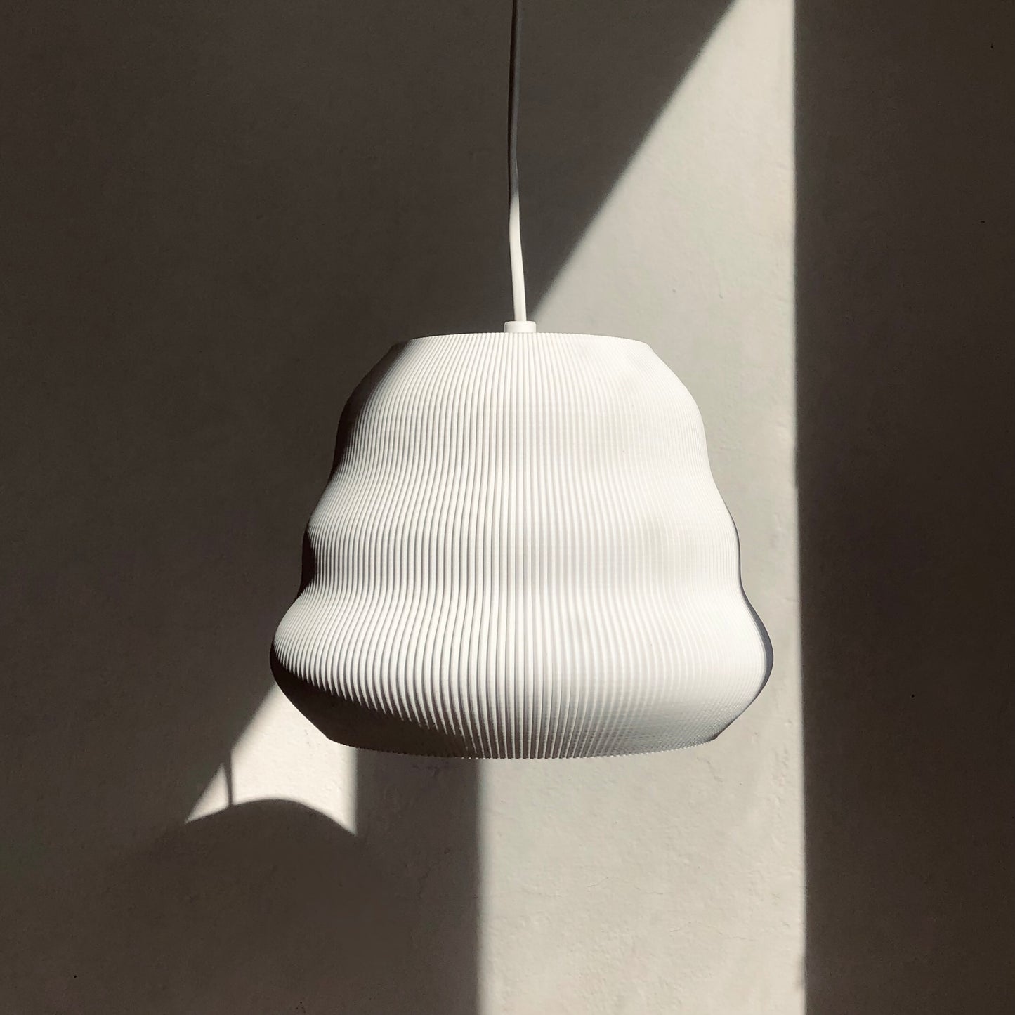 a white lamp hanging from a ceiling next to a wall