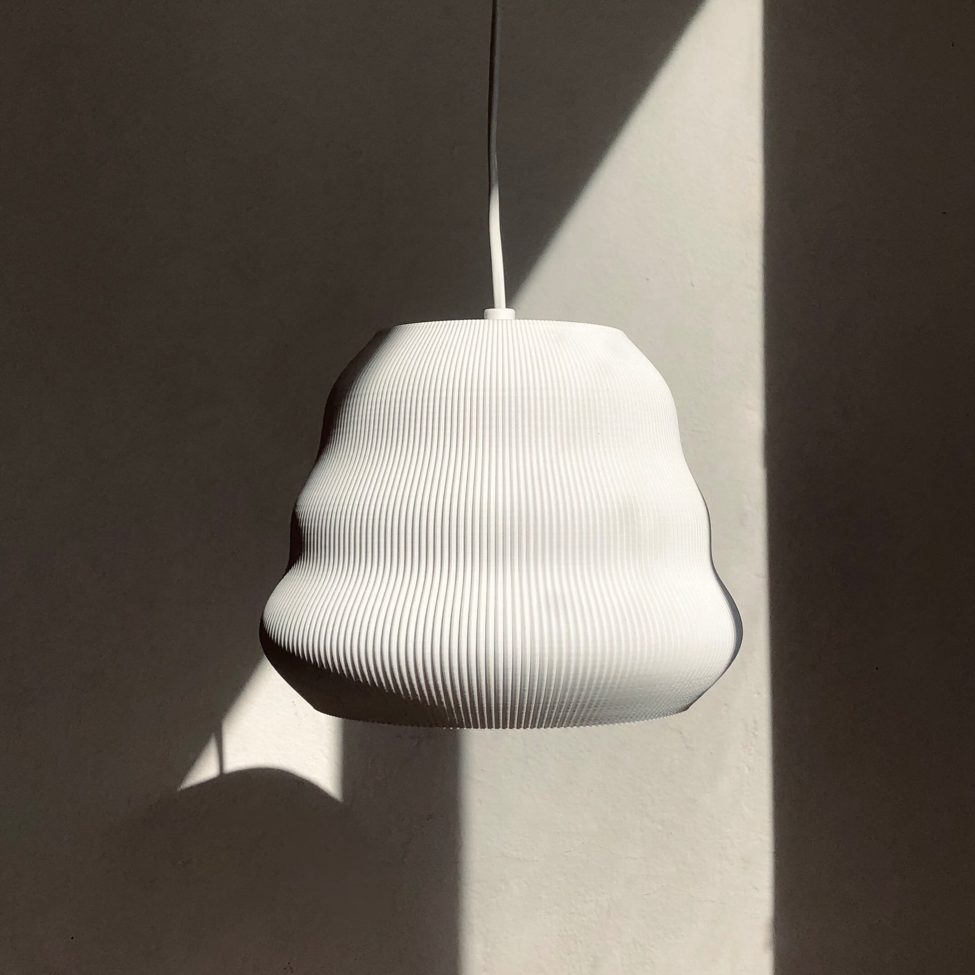 a white lamp hanging from a ceiling next to a wall