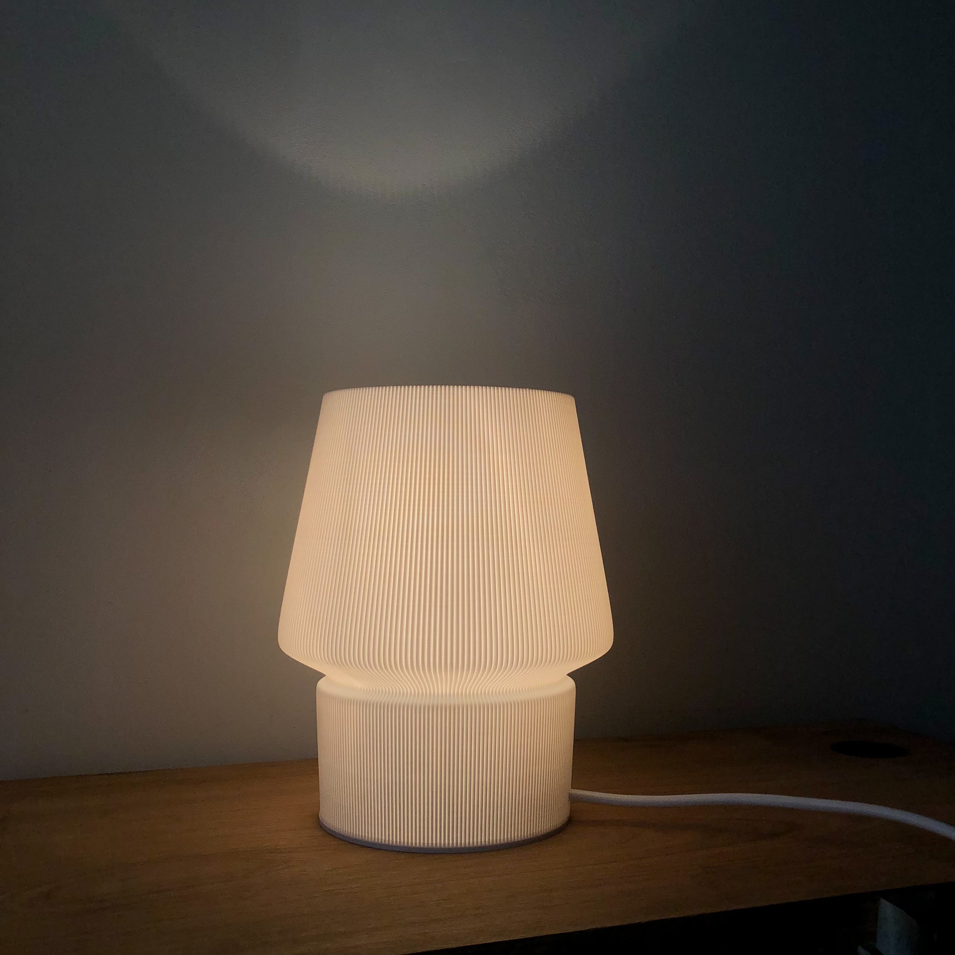 a white lamp sitting on top of a wooden table