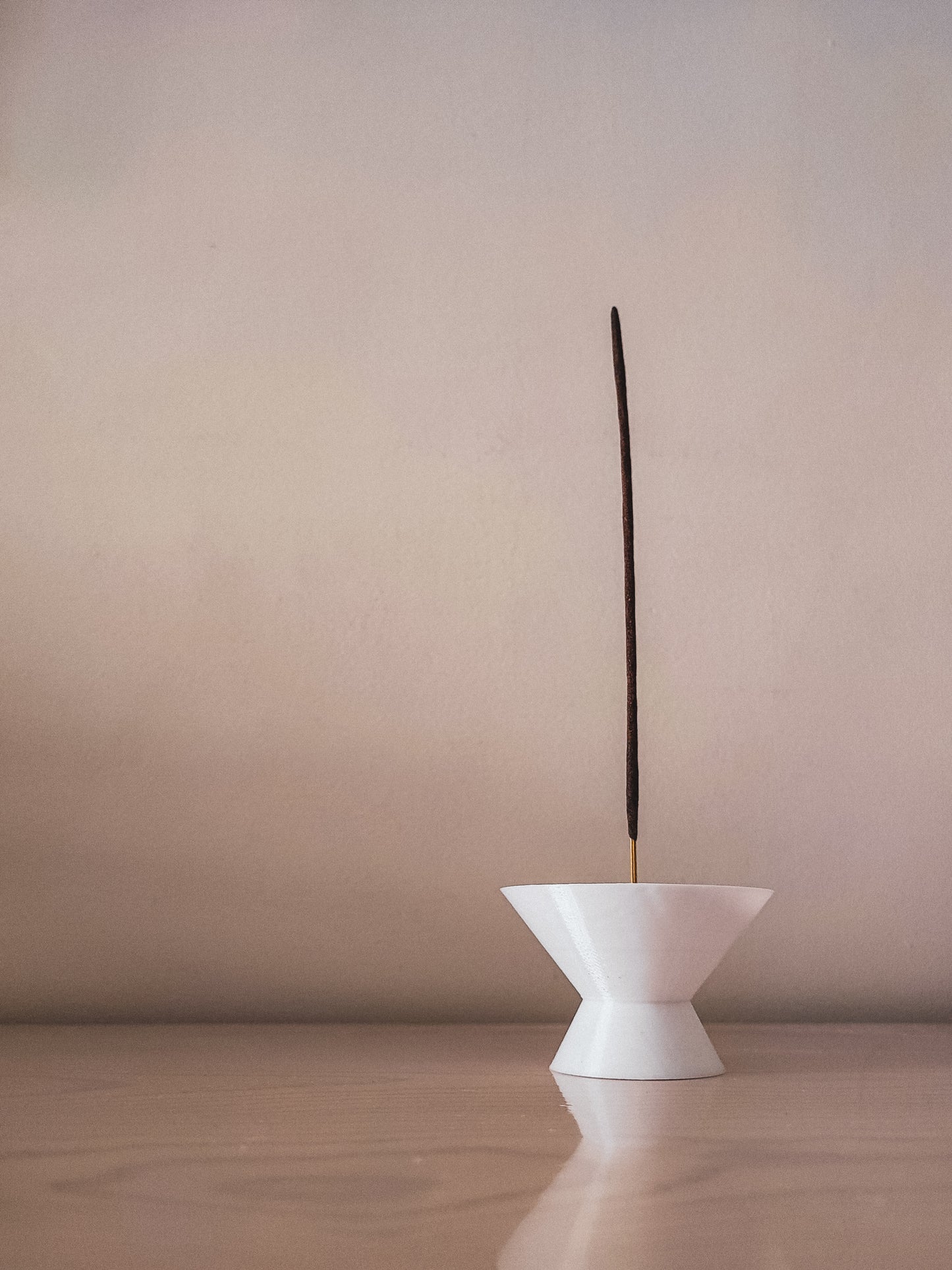 a white vase with a long stick sticking out of it