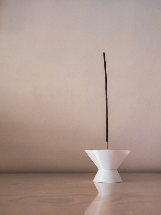 a white vase with a long stick sticking out of it