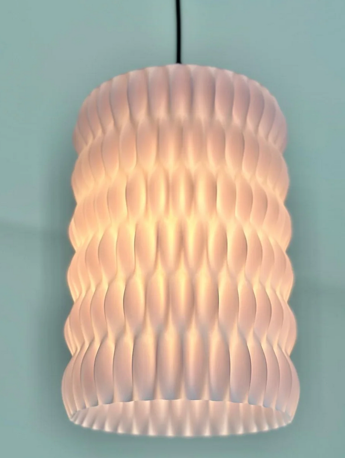 A modern, geometric pendant light with a textured, ribbed design that creates a soft, warm glow.