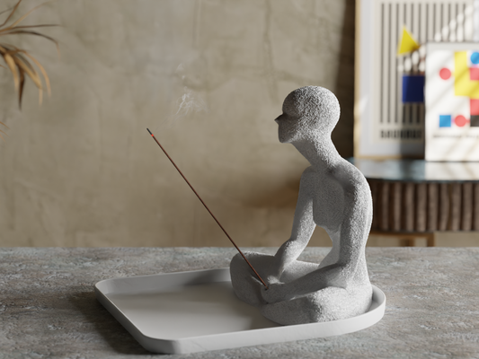 a statue of a man sitting on a tray with a stick in his hand
