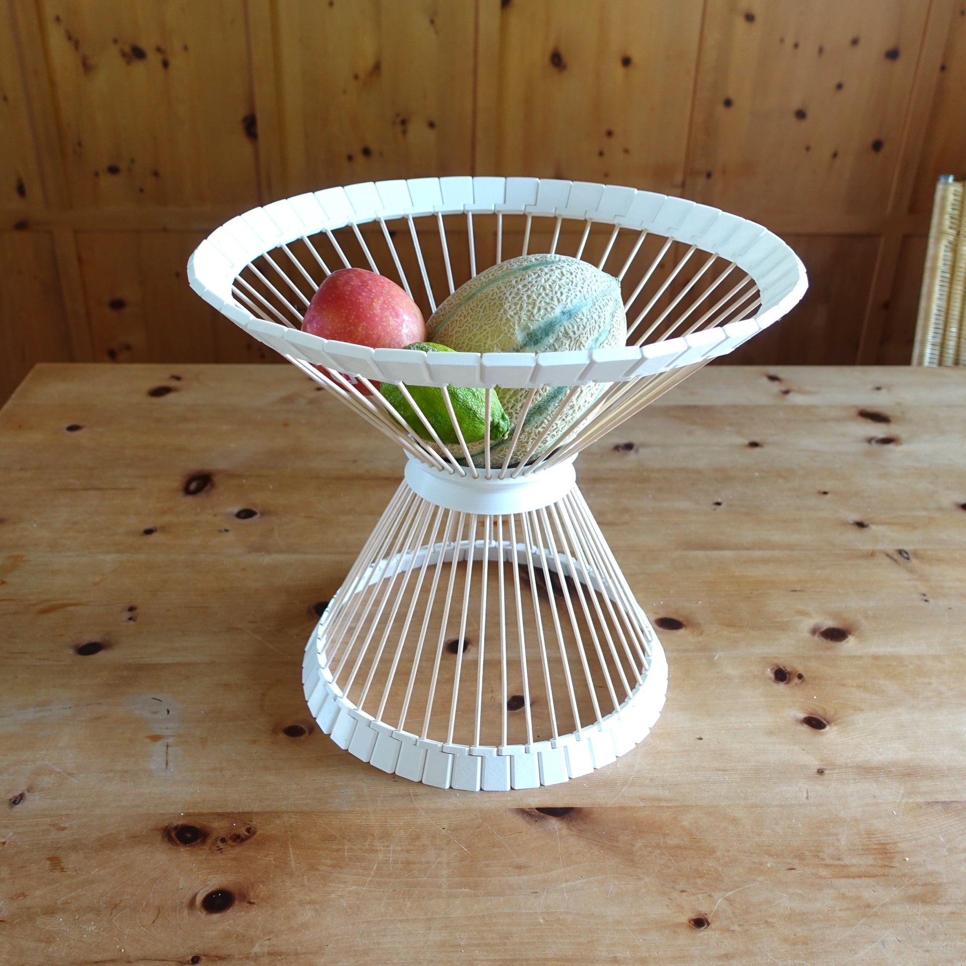 a white wire fruit basket on a wooden table