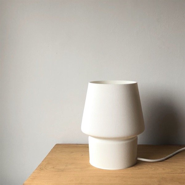 a white lamp sitting on top of a wooden table