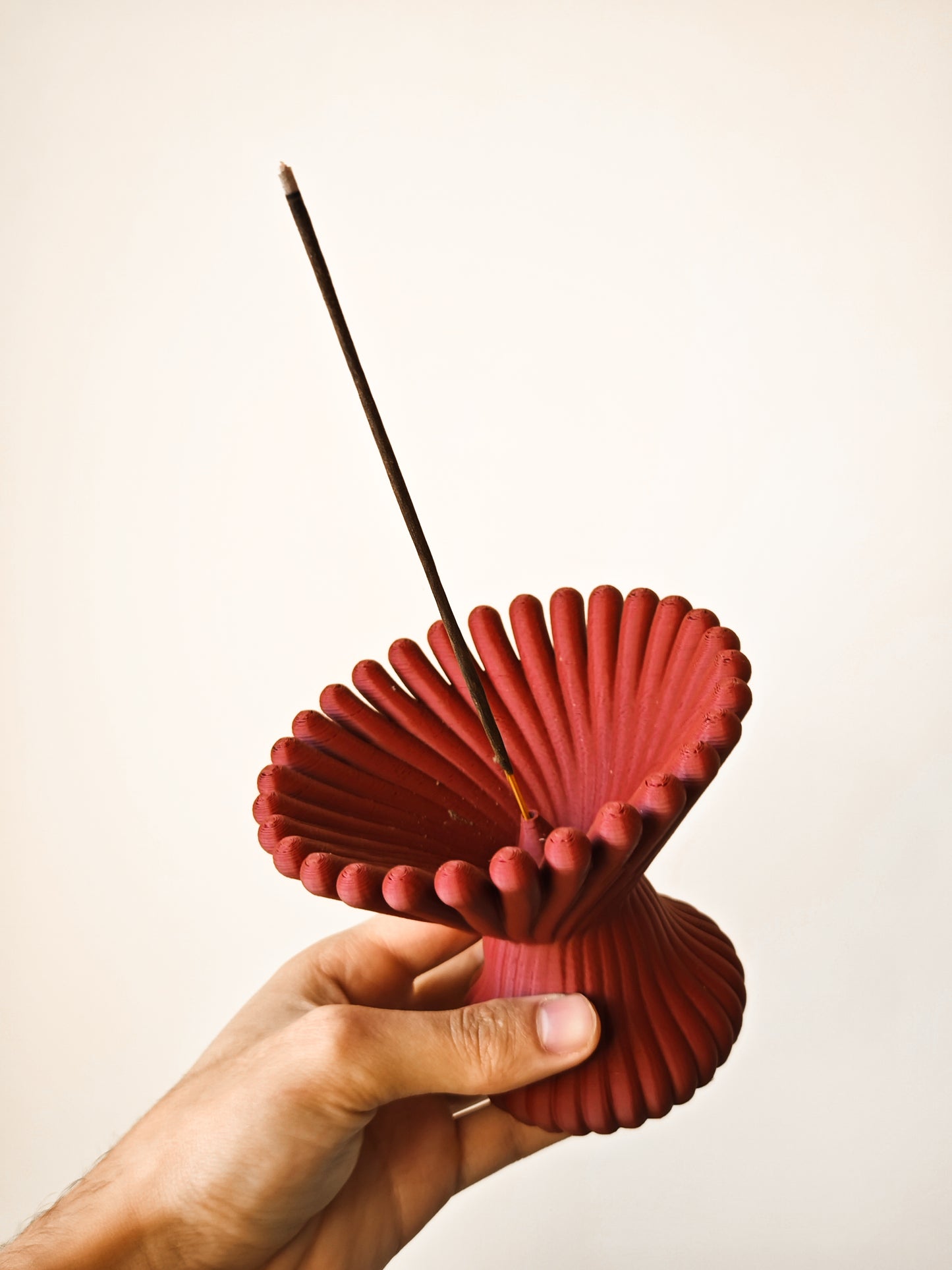 a hand holding a red paper fan with two sticks sticking out of it
