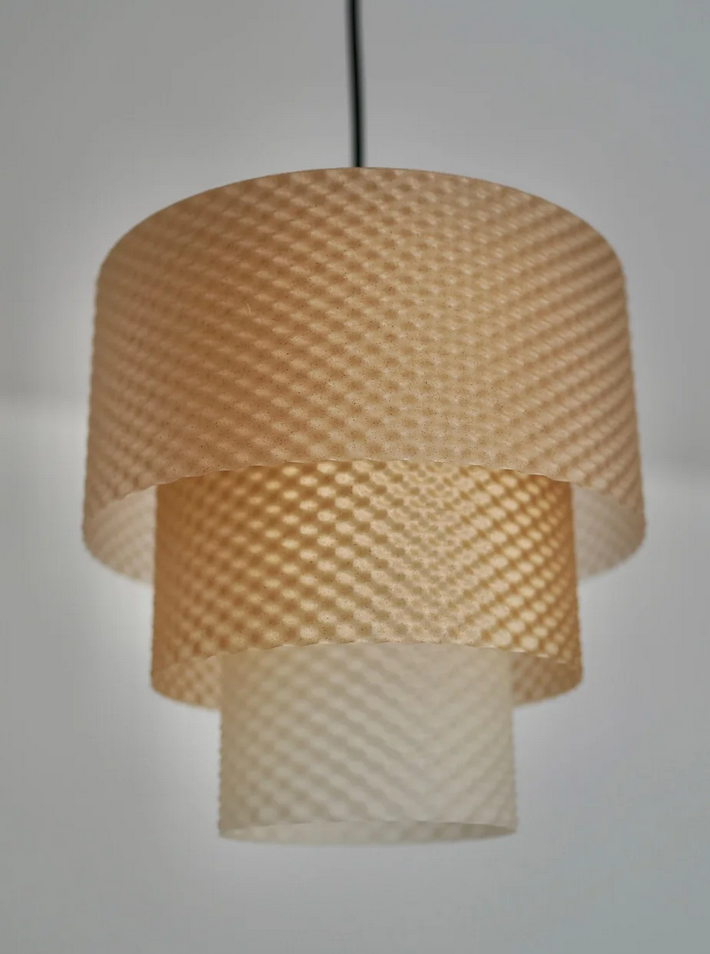 A modern, three-light pendant lamp with a textured, honey-colored shade hangs from the ceiling.