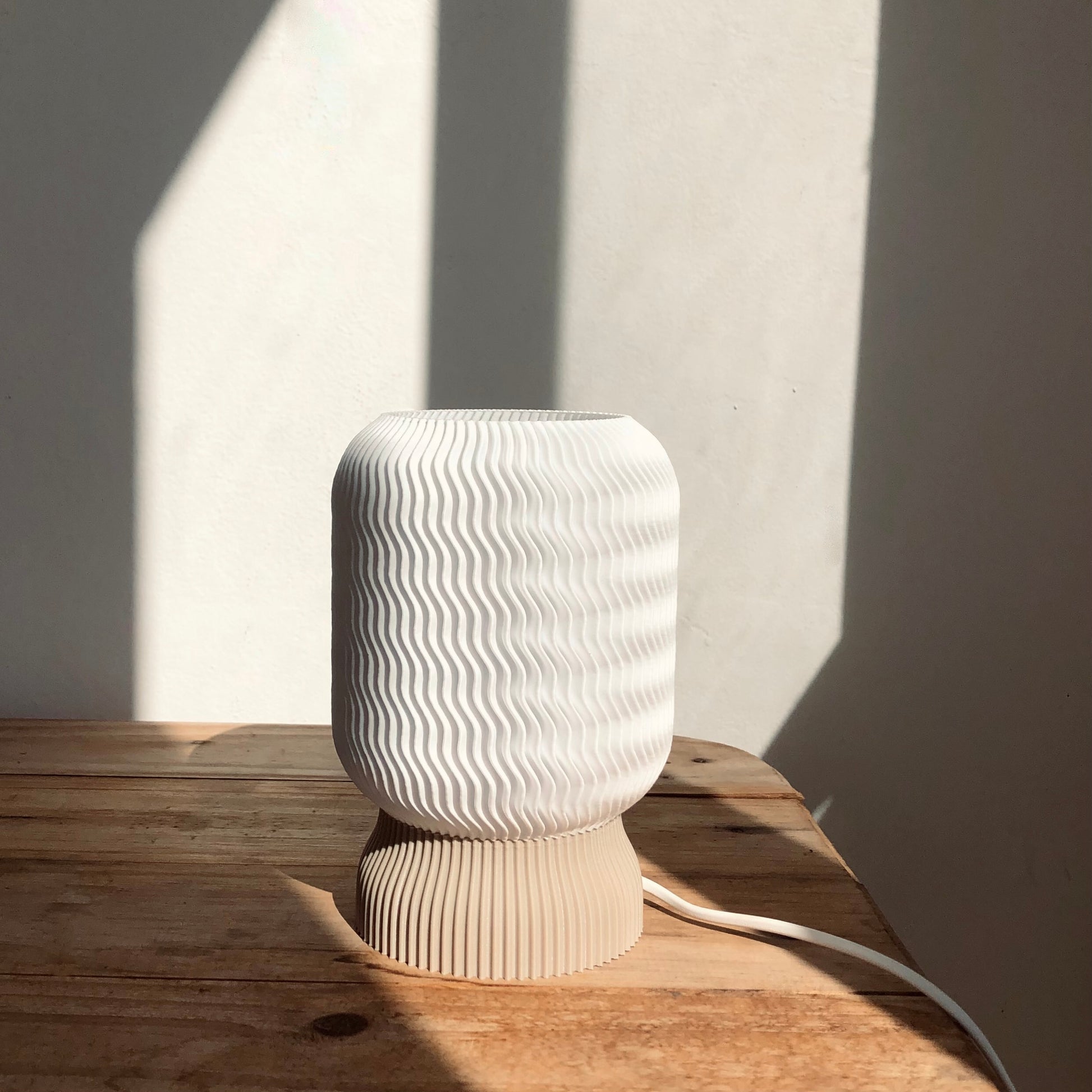 a white vase sitting on top of a wooden table