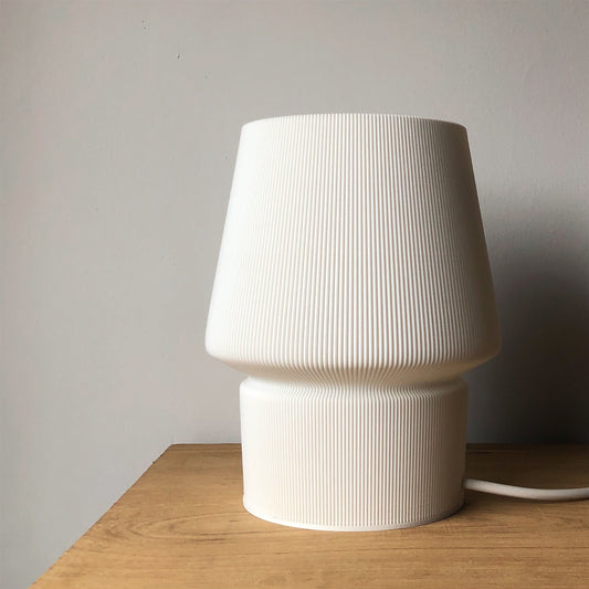 a white lamp sitting on top of a wooden table