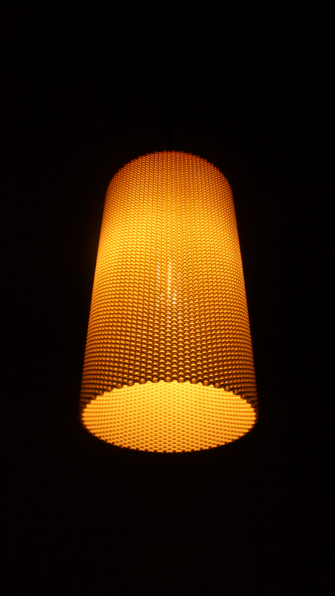 a yellow lamp hanging from a ceiling in a dark room