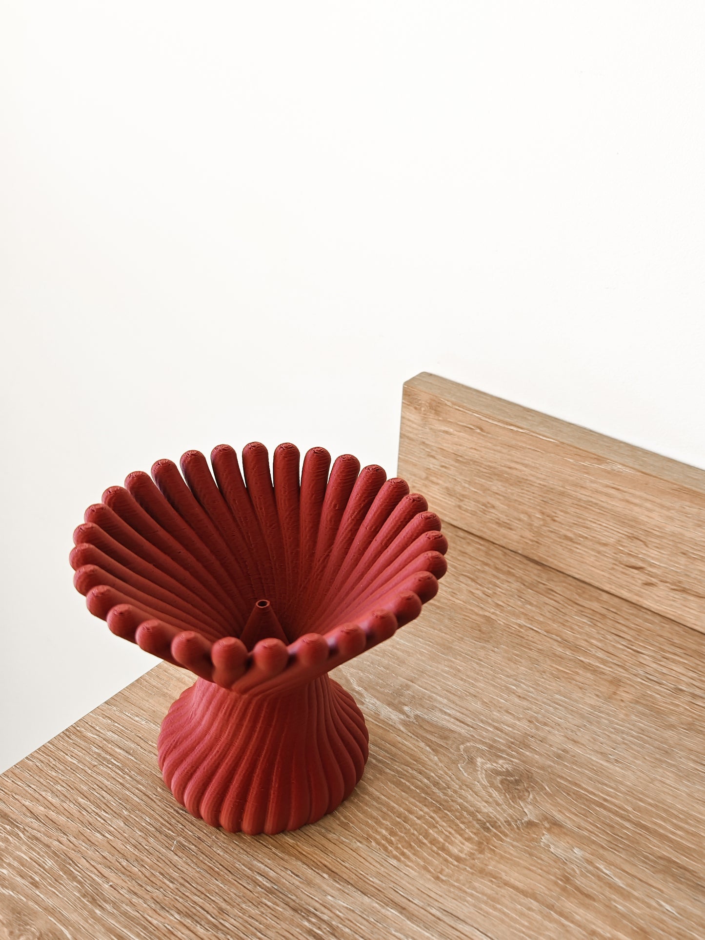 a red vase sitting on top of a wooden table