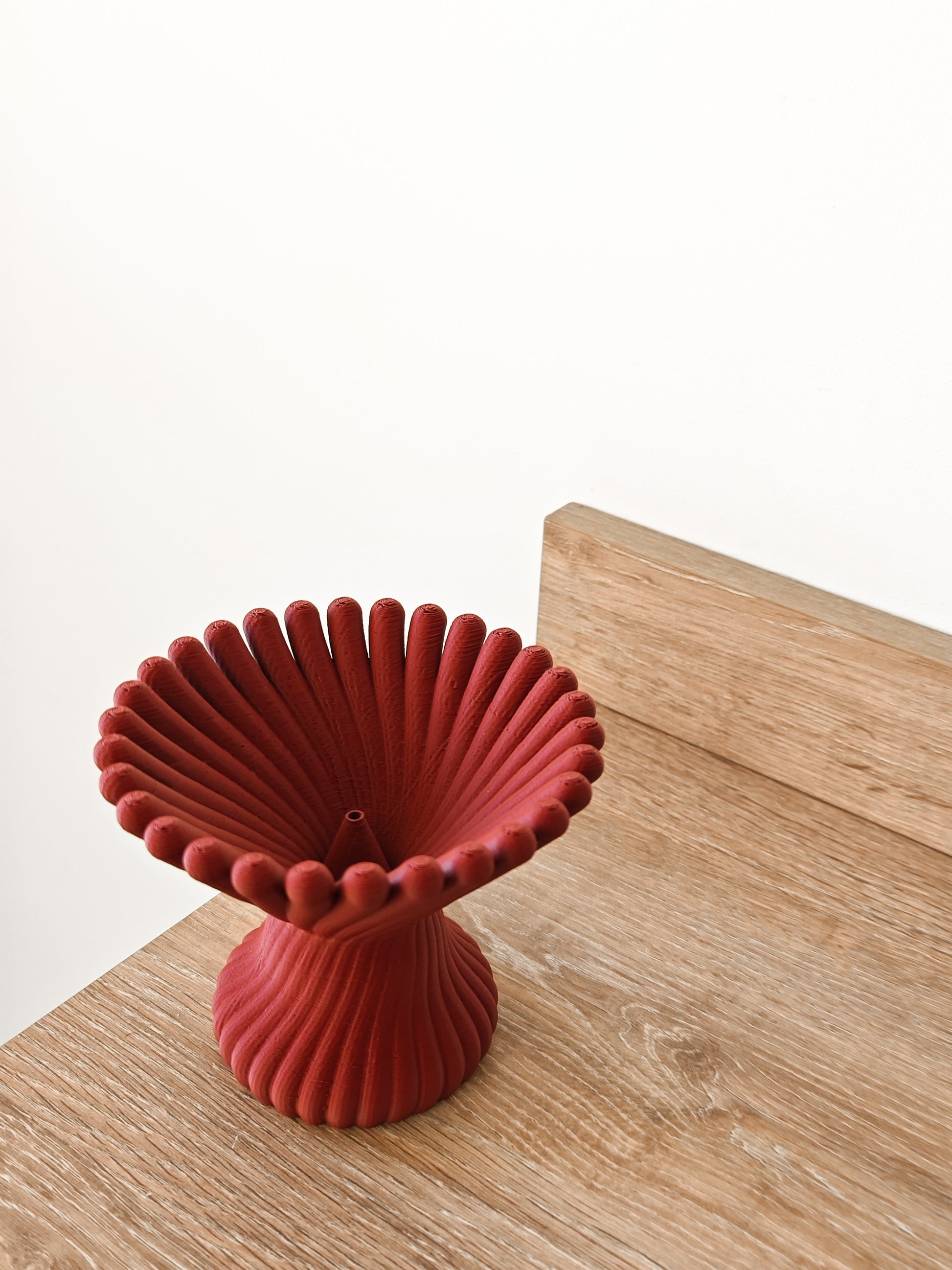 a red vase sitting on top of a wooden table