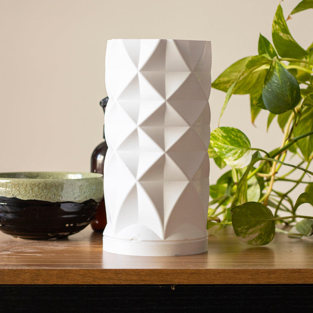 a white vase sitting on top of a wooden table