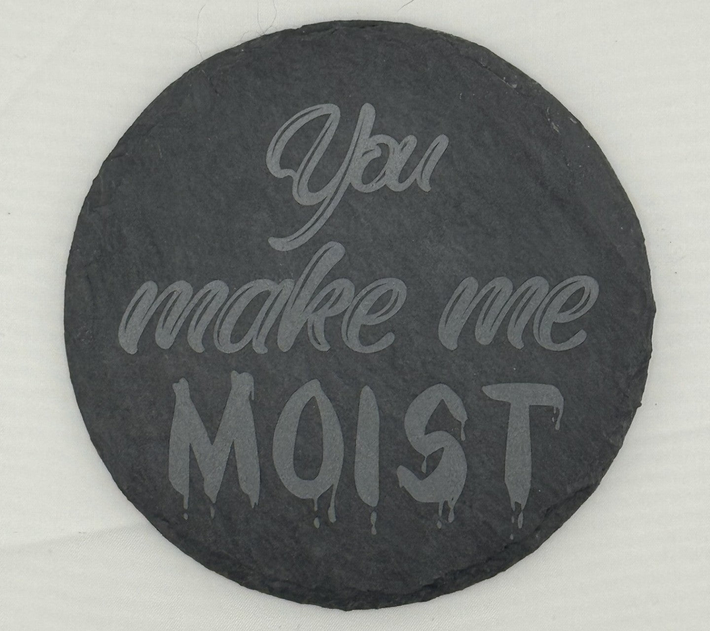 a black stone with the words you make me moist painted on it