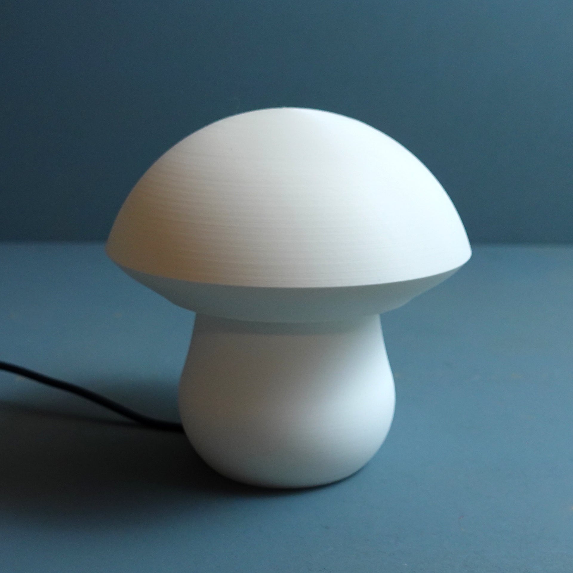 a white mushroom lamp on a blue surface