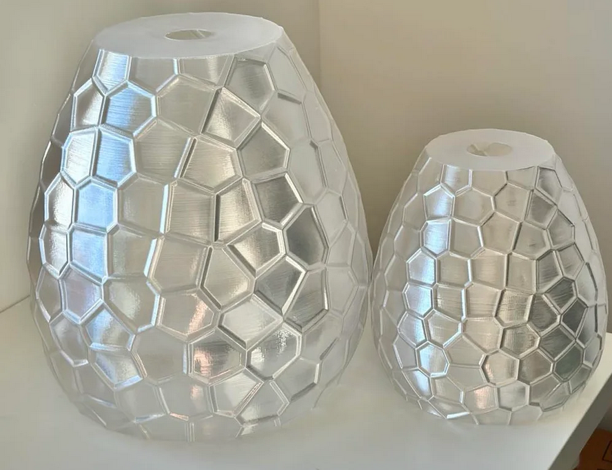 two large, hexagonal glass vases with a metallic, textured surface.
