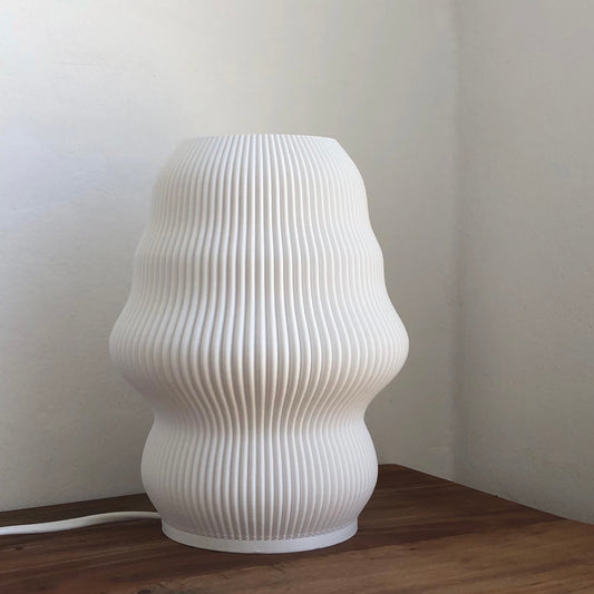 a white vase sitting on top of a wooden table